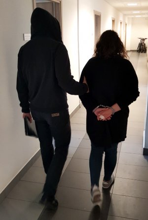 Policjant prowadzący 22-letnią podejrzaną na przesłuchanie