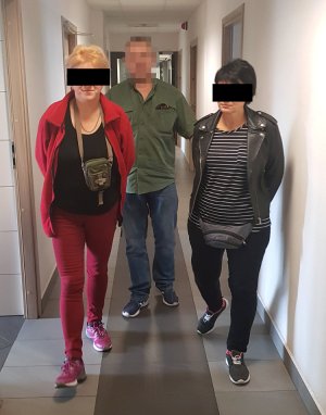 Policjant prowadzi zatrzymane kobiety na przesłuchanie