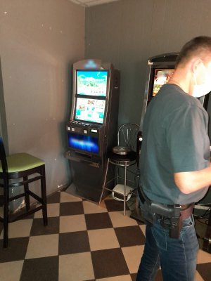 Na zdjęciu widać policjantów zabezpieczających nielegalne automaty do gier hazardowych.