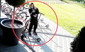 Na zdjęciu widać mężczyznę ubranego w czarną bluzę z kapturem ze wzorami, czarne spodnie dresowe oraz czarne buty z trzema białymi paskami.