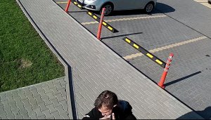 Na zdjęciu widać mężczyznę ubranego w czarną bluzę z kapturem ze wzorami, czarne spodnie dresowe oraz czarne buty z trzema białymi paskami.