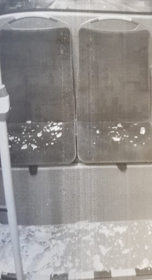 Zdjęcie przedstawią zdjęcia wybitej bocznej szyby w autobusie. Widać na nich fragmenty szkła w ramie okiennej oraz rozrzucone w pobliżu drobne kawałki.