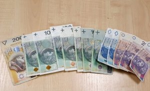 Na zdjęciu widoczne są pieniądze zabezpieczone przez policjantów na miejscu przestępstwa. W formie wachlarza nominałami ułożone sż banknoty 200 zł, 100 zł, 50 zł i 20 zł.