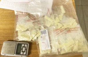 Na zdjęciu widać kilkadziesiąt foliowych woreczków wypełnionych biała substancją, zapiski oraz wagę elektroniczną.