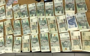 Na zdjęciu widać kilkadziesiąt banknotów o nominałach 100 zł i 50 zł. poukładanych w rzędy .