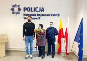 Po prawej stronie umundurowana policjantka - mł.asp. Pauliną Ziobro z Komendy Rejonowej Policji Warszawa II. W środku stoi Pani Weronika z dwoma bukietami kwiatów. Po lewej stronie Filip Chajzer.