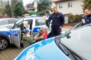 Wilanowscy dzielnicowi rozmawiają z dziećmi Przedszkola Zielony Latawiec na warszawskim Wilanowie, na czym tak naprawdę polega ich praca. Na zdjęciu dzieci w radiowozach oraz trzej umundurowani dzielnicowi - sierżanci sztabowi Bartosz Wysocki, Kamil Tkaczyk i Łukasz Wężowski.