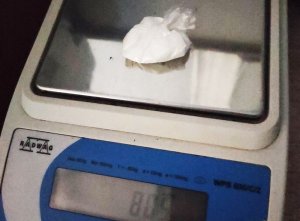 Zdjęcie przedstawia biały proszek w foliowym zawiniątku leżące na blacie wagi elektronicznej, która wskazuje 8,05 grama