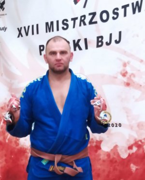 Policjant w granatowym kimono brazylijskiego jiu-jitsu na I miejscu na podium.