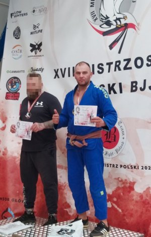 Policjant w granatowym kimono brazylijskiego jiu-jitsu na I miejscu na podium.