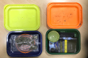 Dwa plastikowe pudełka z zawartością zielono-brunatnego suszu.