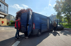 Z lewej stronie na zdjęciu stoi nieumundurowany policjant. Rozmowa z siedzącym przy wejściu do skrzyni załadunkowej mężczyzną zatrzymanym jako podejrzany o kradzież motocykla. Po prawej stronie przy kabinie pojazdu stoi drugi nieumundurowany policjant. Funkcjonariusz zagląda do kabiny pojazdy. Wykonuje on czynności służbowe.