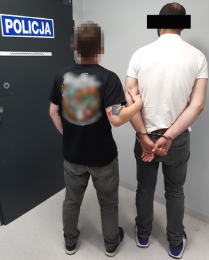 Policjant prowadzi zatryzmanego mężczyznę.