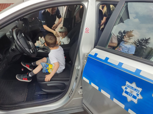 Policjanci prowadzą zajęcia z dziećmi, opowiadając o zawodzie policjanta i bezpieczeństwie. Na zdjęciach dzieci oglądają z bliska i od wewnątrz policyjny radiowóz i wyposażenie służbowe.