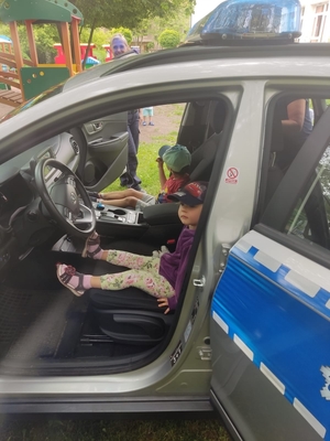 Na zdjęciu policjantka oraz dzieci ze żłobka siedzący w radiowozie policyjnym