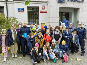 Grupa z dzieci z policjantami przed budynkiem komendy Policji na warszawskim Mokotowie