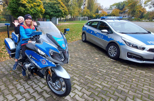 Policjanci z mokotowskiego Wydziału Prewencji oraz stołecznego Wydziału Ruchu Drogowego prezentują policyjne radiowozy, oznakowany motocykl oraz wyposażenie policjantów do służby. Zdjęcia przedstawiają również  gości pikniku, siedzących na motocyklu policyjnym w radiowozie.