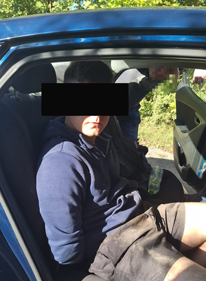 Na zdjęciu widnieje zatrzymany mężczyzna siedzący na tylnym siedzeniu w samochodzie