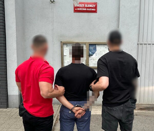 Policjanci z osobą zatrzymaną, która ma na rękach kajdanki