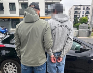 Policjanci z osobą zatrzymaną, która ma na rękach kajdanki