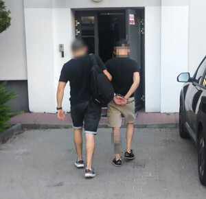 Policjant prowadzi osobę zatrzymaną