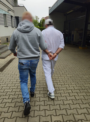 Policjant prowadzi osobę zatrzymaną
