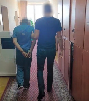 Policjant prowadzi osobę zatrzymaną