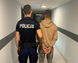 Umundurowany policjant prowadzi zatrzymanego