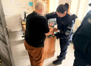 Umundurowana policjantka wykonuje czynności z zatrzymanym
